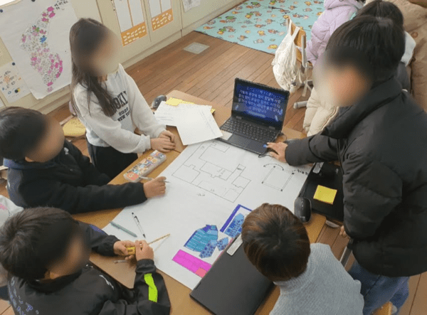 학생들이 태블릿과 종이를 함께 쓰며 모둠 프로젝트를 진행하는 교실 장면