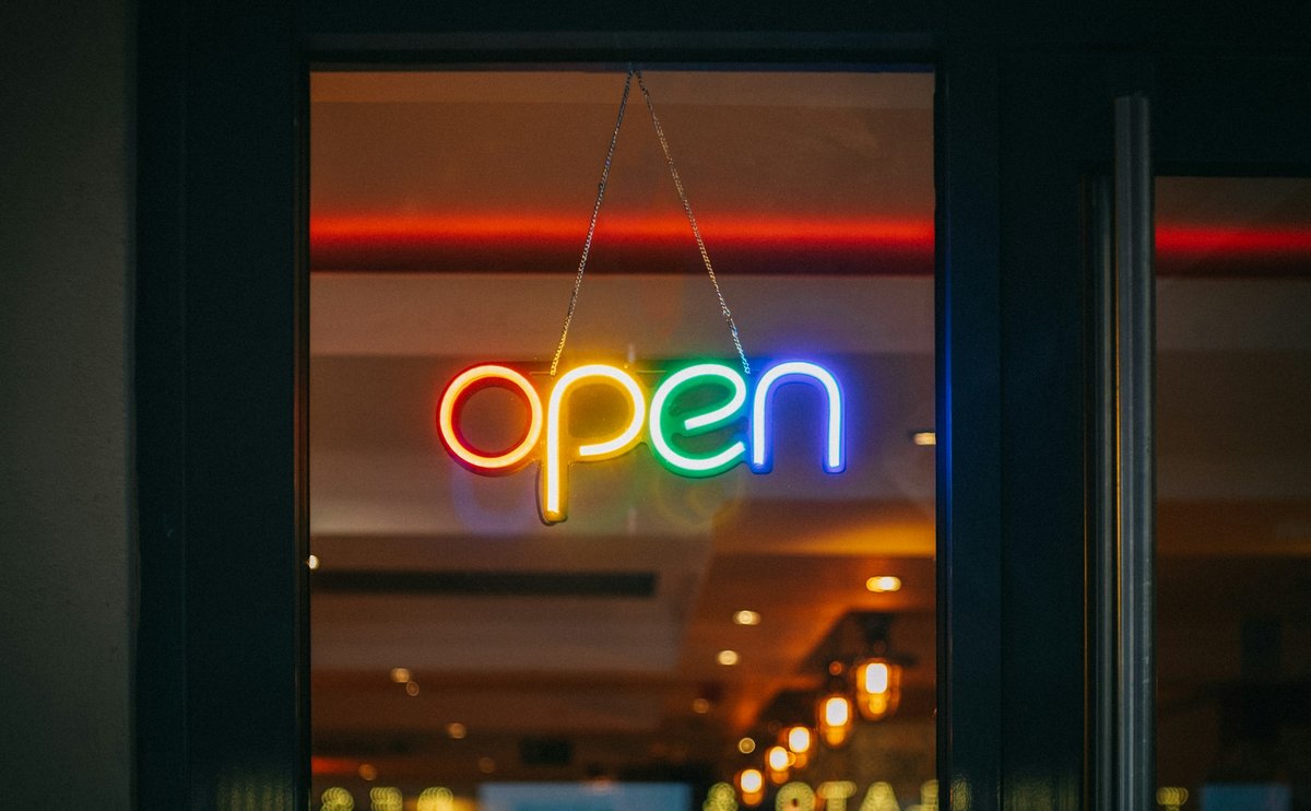 유리문 안쪽에 걸린 무지개색 open 네온 간판