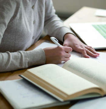 학생이 책상에 앉아 글을 쓰고 있음